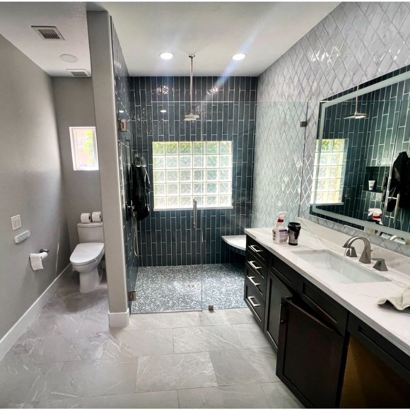 Modern bathroom with large glass shower, dark cabinets, and sleek tiles under recessed lighting.