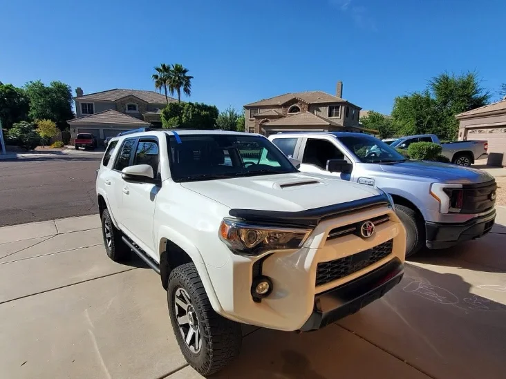 A white Toyota 4Runner parked in a sunny driveway, showcasing its rugged design and modern style.