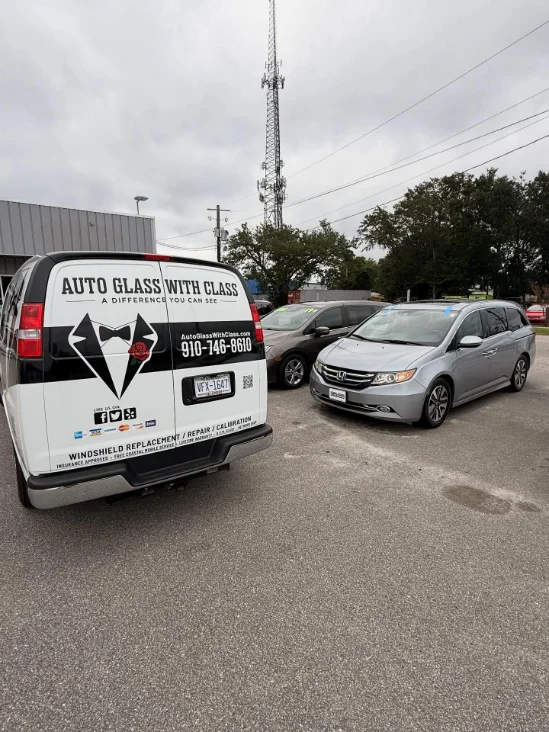 Van for Auto Glass With Class parked with vehicles nearby, promoting windshield replacement and repair services.